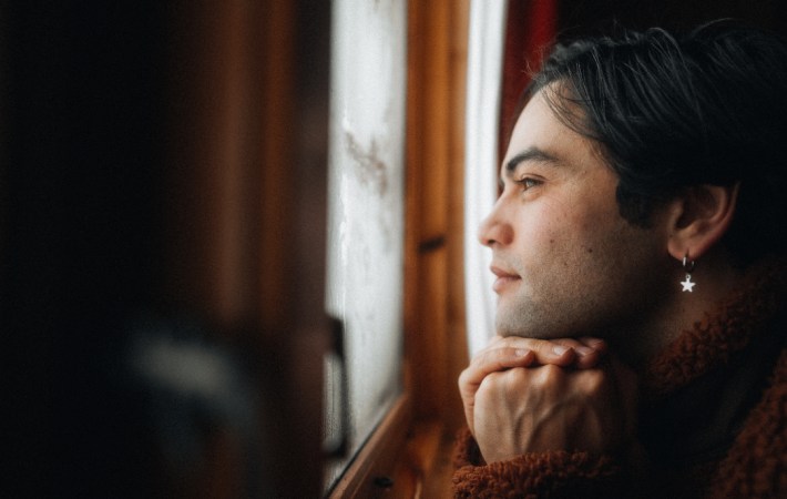 Photo of Indonesia-born, singer/songwriter Hilang child, now calling London, UK his home. The photo shows the artist pensive in profile, all in warm brown tones.