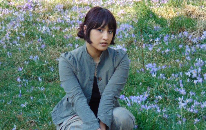Press shot of London pop-artist Aniwa showing the artist sitting in a blooming meadow