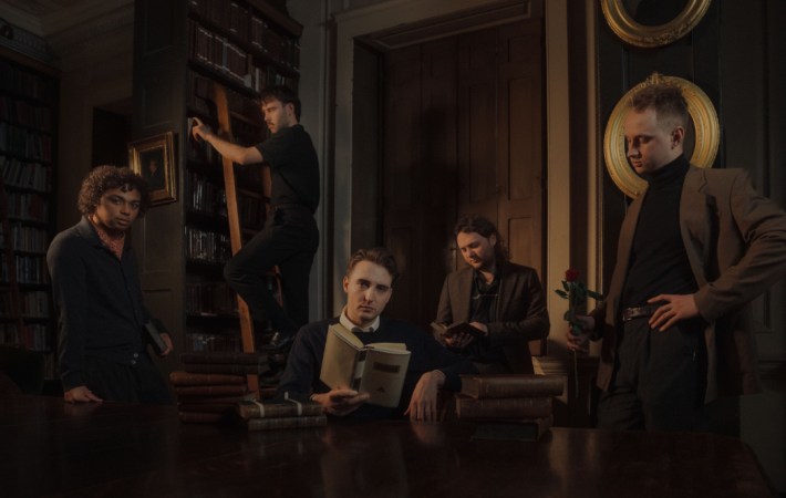 Pressshot of the Nottingham, England based band Victory Lap - it shows the five male members in a library, in a very moody setting and light